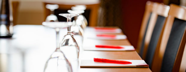 Image of table set up with notepads, glasses and water
