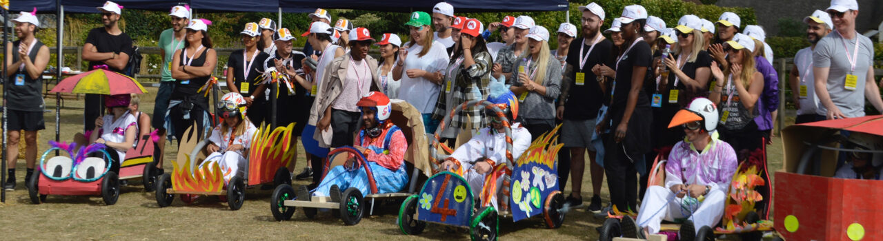 Fun corporate event with people dressed casually grouped around some DIY go karts.