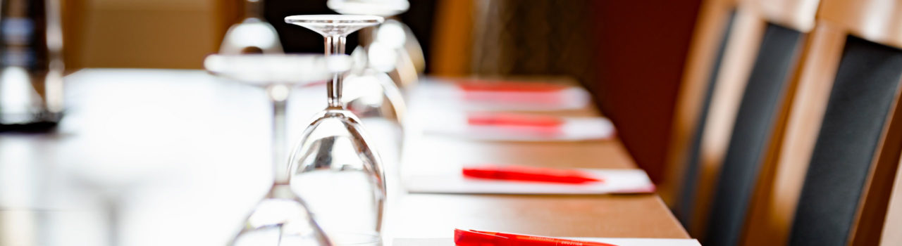Image of table set up with notepads, glasses and water