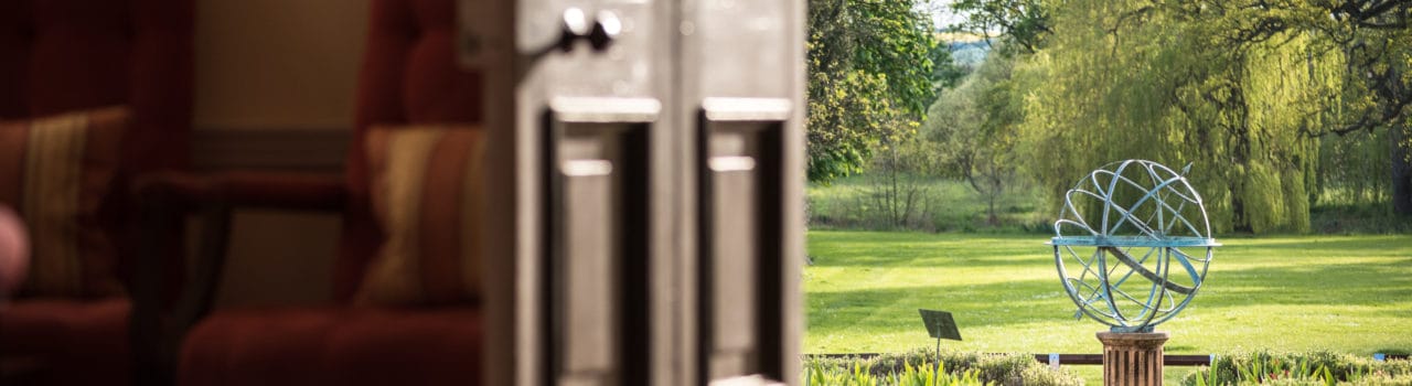 Image of open door looking out at globe sculpture outside Hinxton Hall