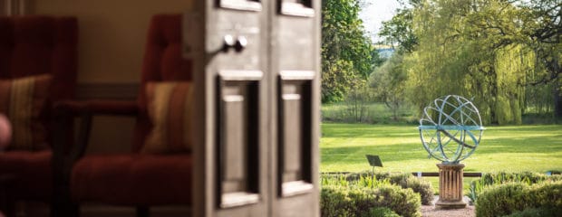 Image of open door looking out at globe sculpture outside Hinxton Hall