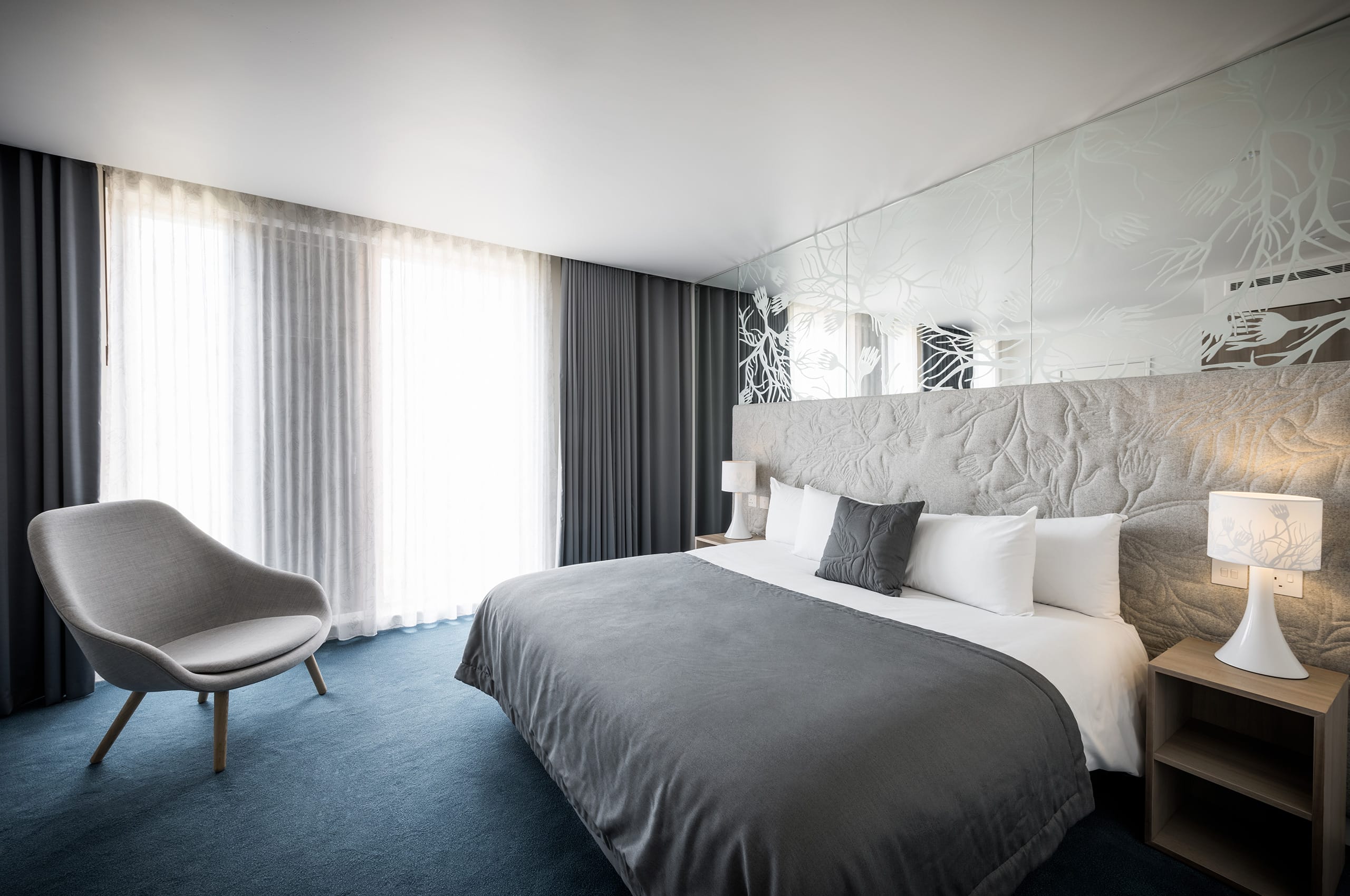 An example of a hotel room in Mulberry Court, featuring a large double bed, a chair, side table and lamps.