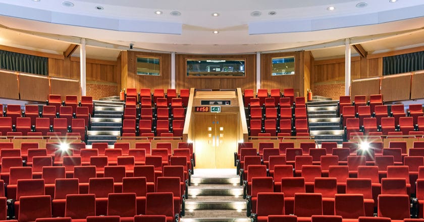 Francis Crick Auditorium, looking towards the technicians booth. Bright read matt seats, and lights gleaming.