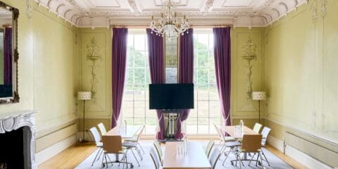 A photo of our Green Room, a beautiful historic room with green walls, a fireplace and an ornate ceiling.