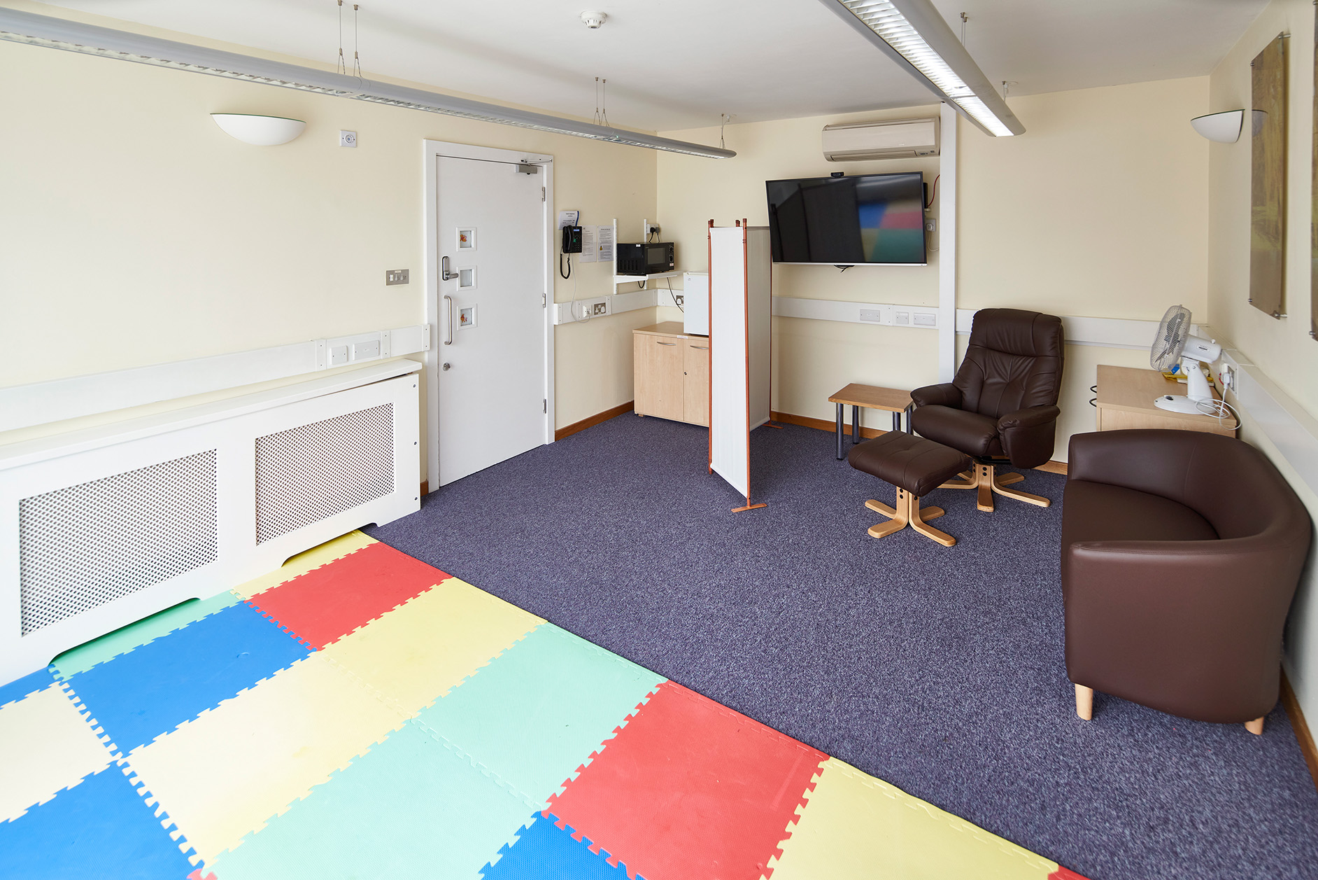 Photo of the Family Room comprising comfortable seating and a padded play area.
