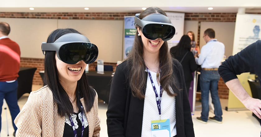 Two smiling, female delegates wearing VR headsets at Cam Tech Week