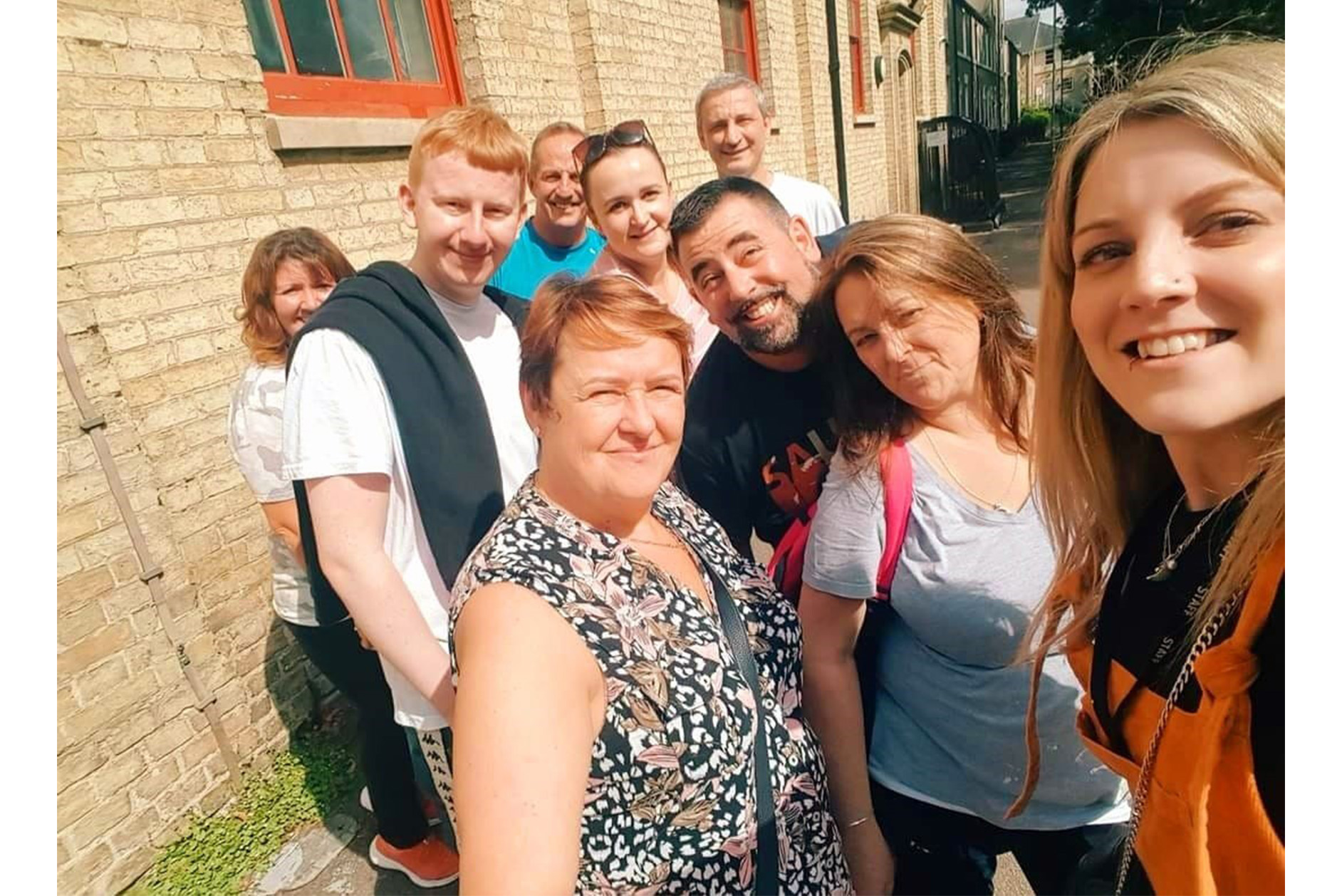 Group selfie shot of nine staff members outside Jimmy's night shelter, Cambridge