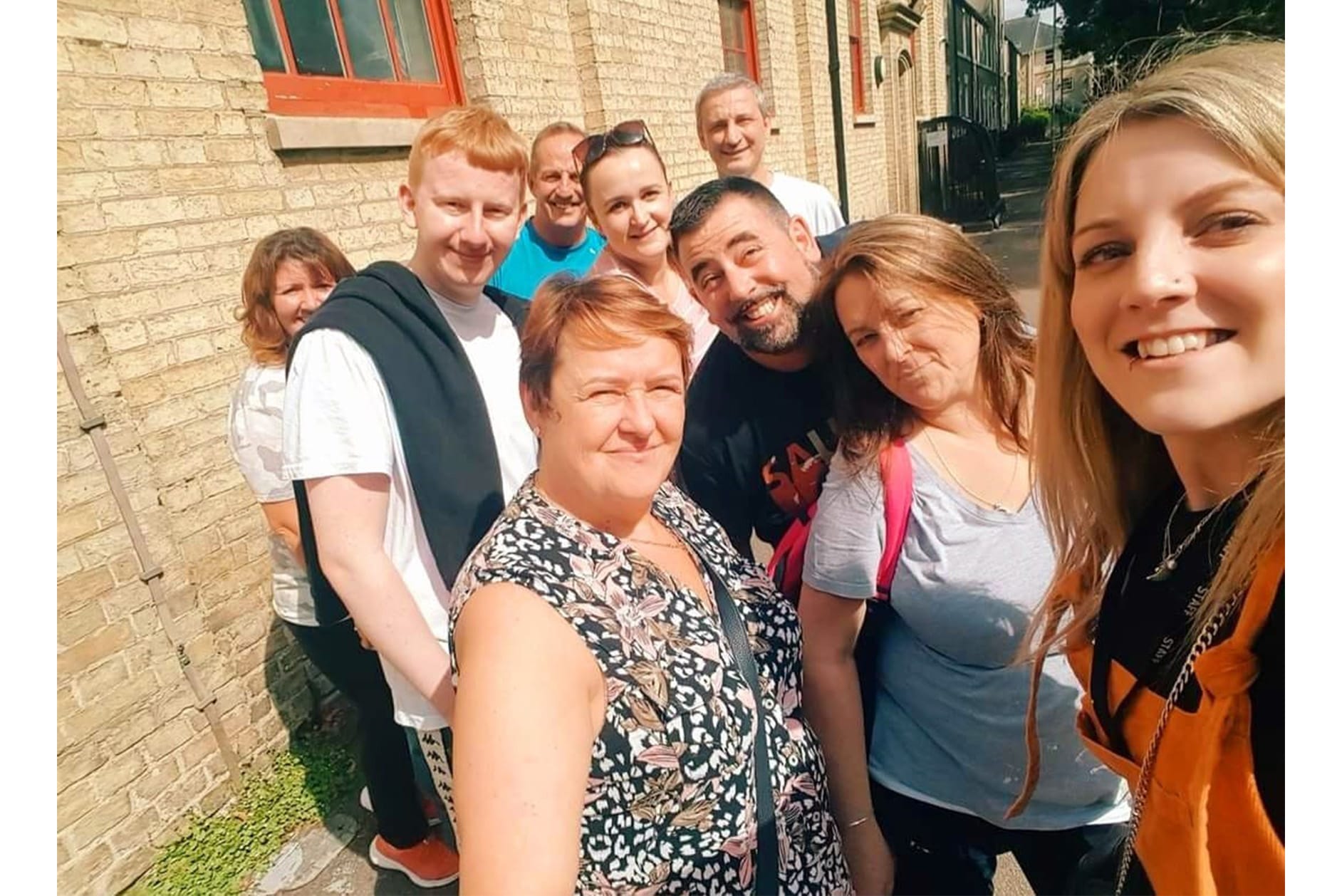 Group selfie shot of nine staff members outside Jimmy's night shelter, Cambridge