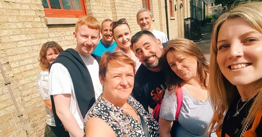 Group selfie shot of nine staff members outside Jimmy's night shelter, Cambridge