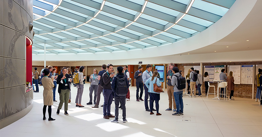 Conference delegates enjoying networking time during break in the Event Space. Above them is a glass and steel roof letting in light.