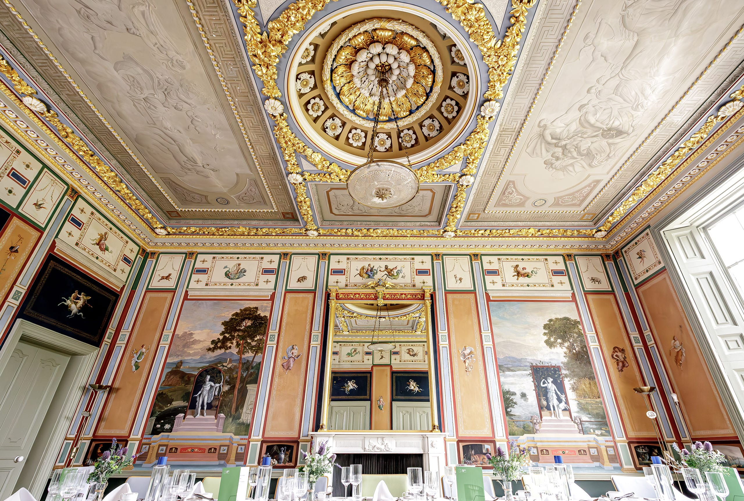 One ornate wall and ceiling decorated in vivid colours and gold leaf. Figurative panels inspired by wall paintings excavated from the mid-eighteenth century onwards in Pompeii and Herculaneum. One ornate wall and ceiling decorated in vivid colours and gold leaf. Figurative panels inspired by wall paintings excavated from the mid-eighteenth century onwards in Pompeii and Herculaneum.