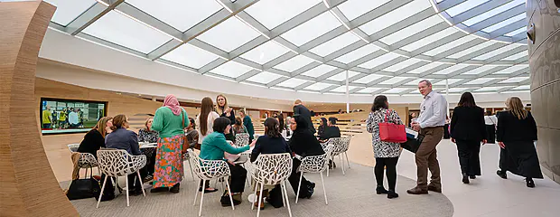 Delegates attending BIA Women in Tech 2025 sitting in groups around small tables in a space partially enclosed by a wooden wrap.
