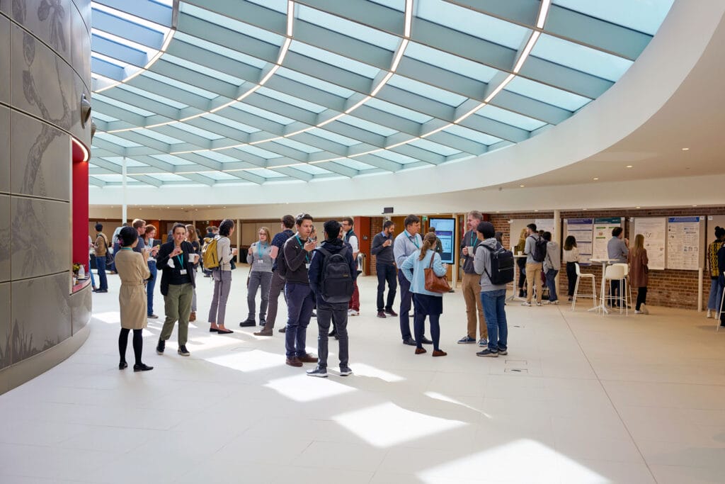 A large group of people are talking and networking in our Event Space within Hinxton Hall Conference Centre.