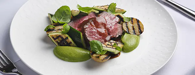 A photo of a fine dining meal with red meat and vegetables.