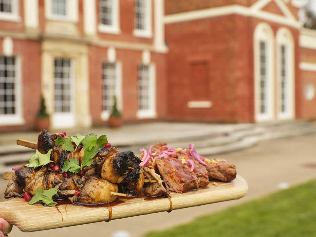 BBQ meat on a board, in front of Hinxton Hall.