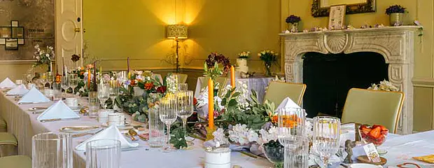 A table set up for a wedding breakfast at Hinxton Hall with flowers and candles